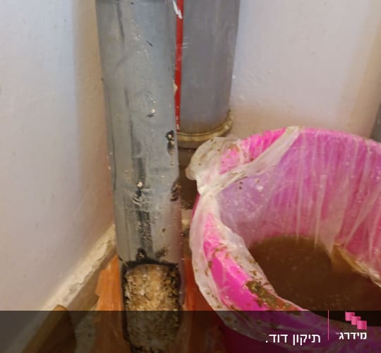 צינור עם דליפה ודלי ורוד מלא במים